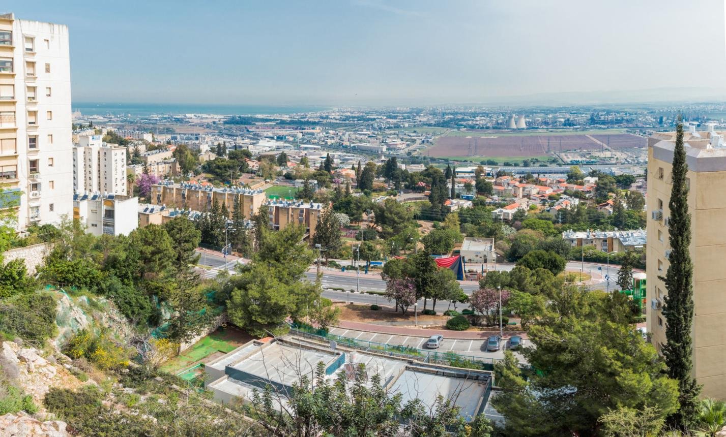 נשר נוף עירוני באור יום עם שכונות מגורים והרים מסביב