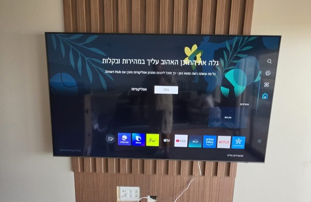 טלוויזיה 75 אינץ' מותקנת על זרוע מפרקית עם קיר עם קיר חיפוי פלסטיק בסלון בנשר