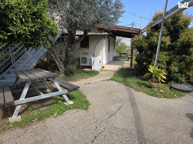 בית פרטי מטופח במושב בן עמי, לצדו ניצב ספסל עץ בגינה הירוקה והשקטה.