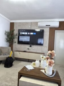 התקנת טלוויזיה חכמה על חיפוי קיר דקורטיבי בקרית אתא, מתקין מסכים מקצועי בחיפה עם הסתרת כבלים מעל מזנון מעוצב.