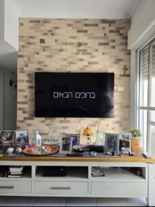 מתקין טלוויזיה בקרית מוצקין וקרית ביאליק - התקנת מסך על קיר חיפוי בריקים מעל מזנון לבן