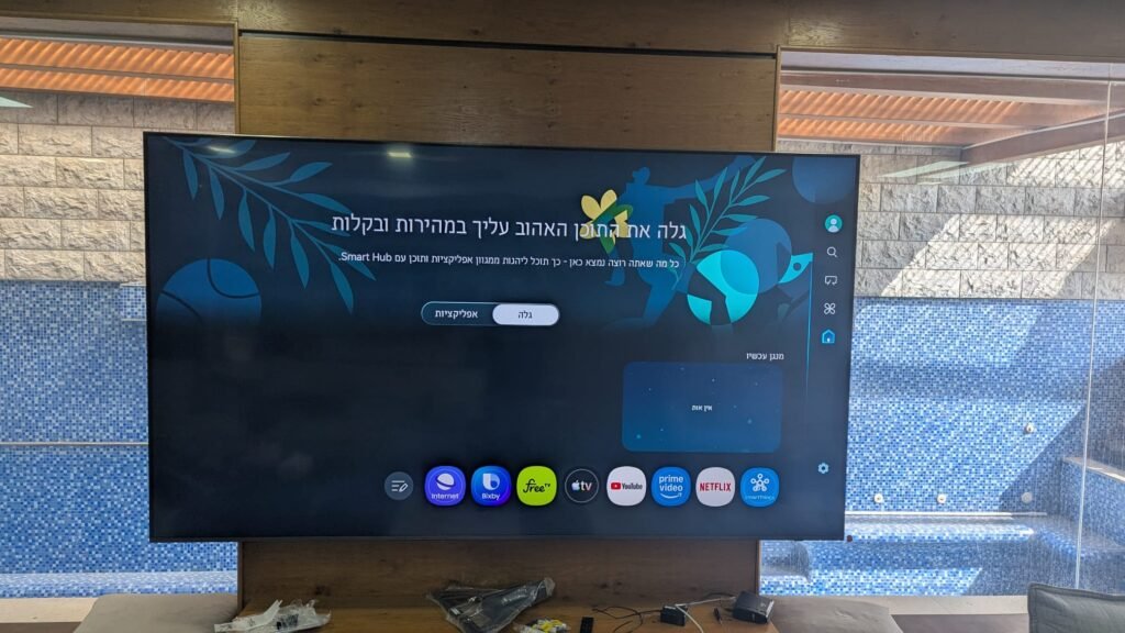 טלוויזיה 100 אינץ' מותקנת על זרוע וקיר חיפוי עץ ובטון בסלון בקרית חיים