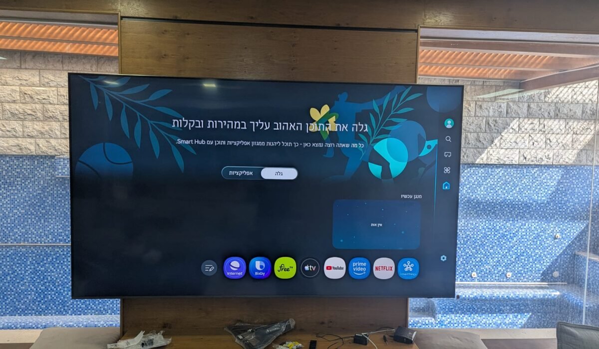 טלוויזיה 100 אינץ' מותקנת על זרוע וקיר חיפוי עץ ובטון בסלון בקרית חיים