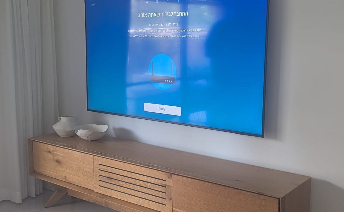 התקנת טלוויזיה על קיר בחיפה מעל מזנון עץ מעוצב.