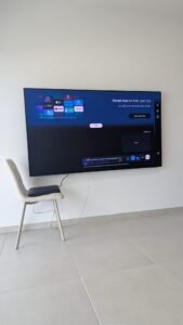 התקנה צמודת קיר של מסך 77 אינץ' OLED בקריות, כולל סידור יחידת One Connect לדירה חדשה.