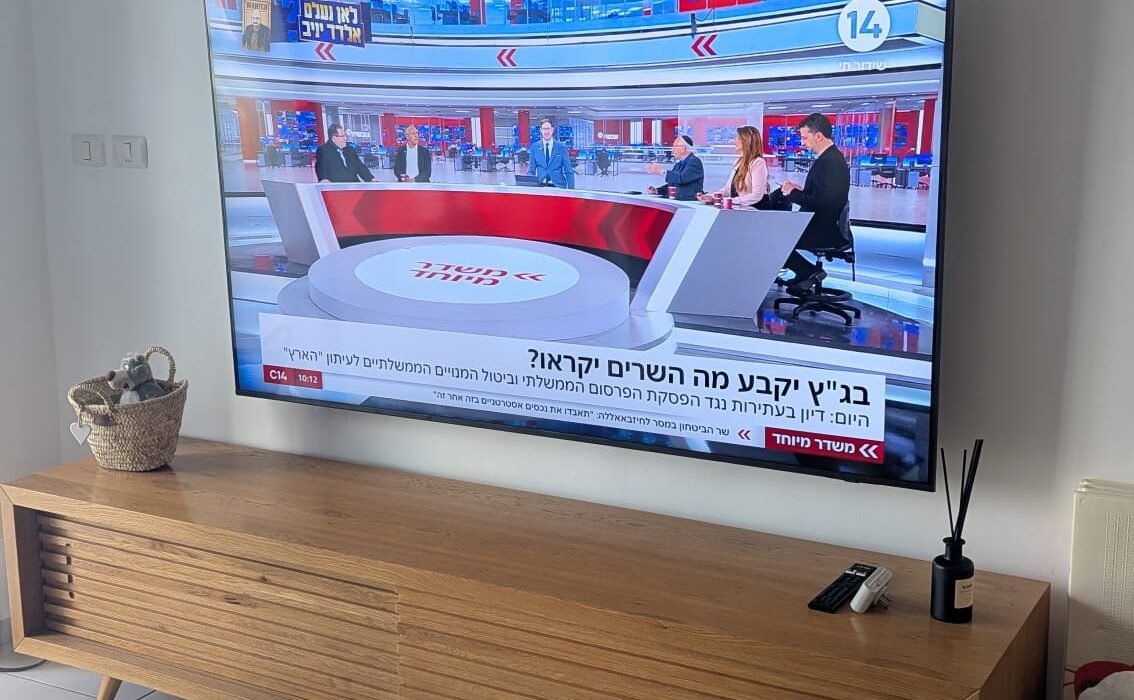 התקנת מסך 75 אינץ' על זרוע מתכווננת מעל מזנון חום כרמל, עבודה מקצועית בחיפה.